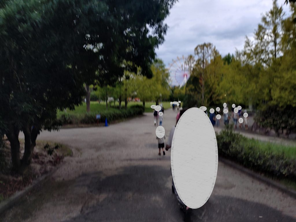 エントランスから坂道を降りてこども動物園のほうに向かう道。遠くには隣接する遊園地の観覧車が見える